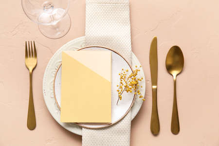 Stylish table setting with blank card and mimosa flower on color background