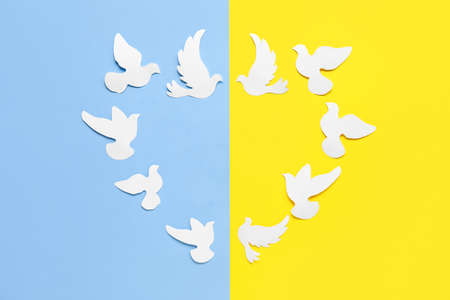 Heart made of paper doves on blue and yellow background. Save Ukraine