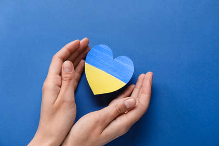 Hands and heart in colors of Ukrainian flag on blue backgroundの写真素材