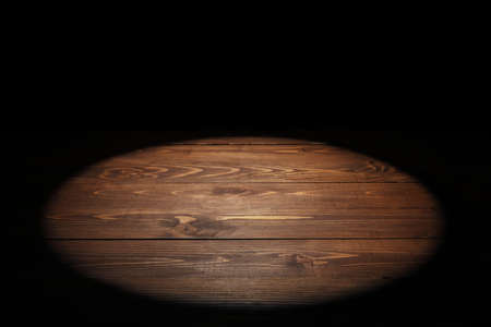 Wooden table top with backlight on black background
