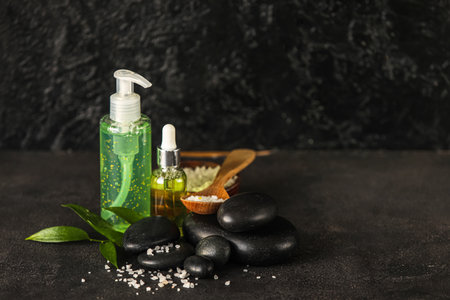 Composition with bottles of cosmetic products, sea salt and spa stones on dark backgroundの写真素材