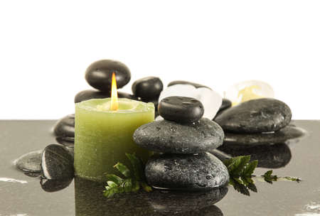 Spa stones and burning candle in water on white backgroundの写真素材