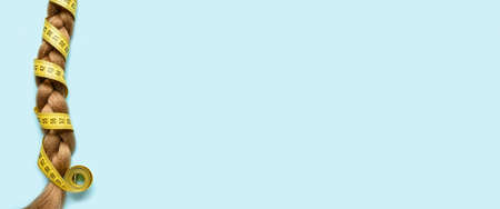 Braided hair and measuring tape on light blue background with space for text
