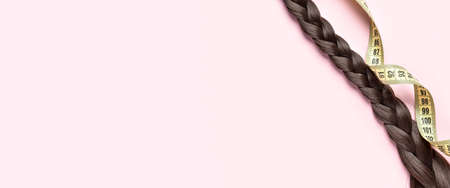 Braided hair and measuring tape on light pink background with space for text
