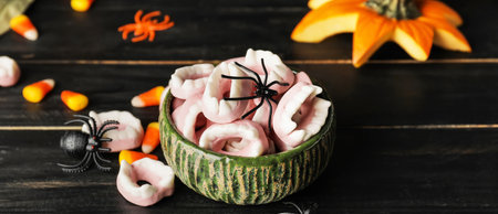 Bowl with tasty candies for Halloween on dark wooden background