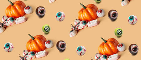 Different creepy candies for Halloween with pumpkins on color backgroundの写真素材