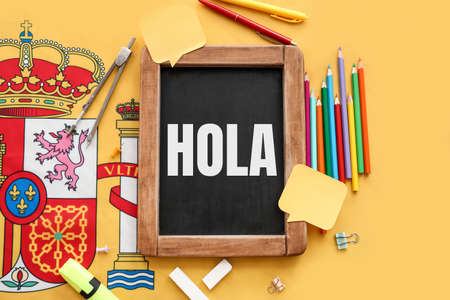 Chalkboard with text HOLA (HELLO) and stationery on yellow background