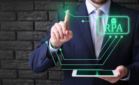 Businessman with tablet computer using virtual screen on dark background. RPA conceptの写真素材