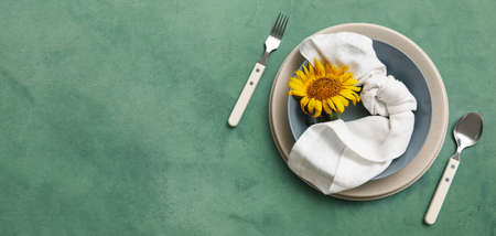 Beautiful table setting with fresh sunflower on green background with space for text, top view
