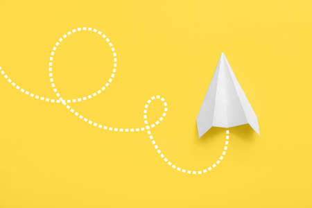 Paper plane on yellow background, top view