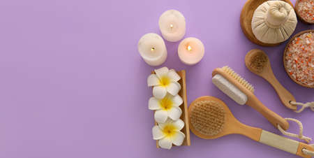 Set of bath supplies, flowers and candles on purple background with space for text