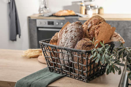 Basket with loaves of fresh bread on table in kitchenの写真素材