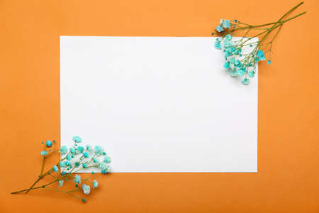 Blank paper sheet with beautiful flowers on orange backgroundの写真素材