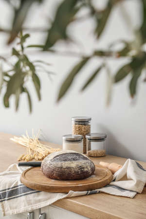 Board with fresh bread on kitchen counter near gray wall