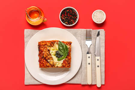 Plate with piece of tasty Italian pie, spices and oil on red backgroundの写真素材