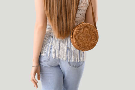 Woman with rattan bag on light background