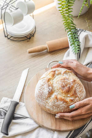 Woman with fresh bread on counter in kitchen