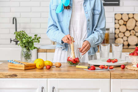 Woman preparing strawberry lemonade on kitchen counter