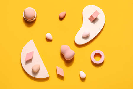 Makeup sponges with decor on yellow background