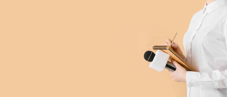 Journalist with microphone and notebook on beige background with space for textの写真素材
