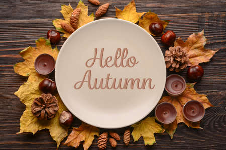 Autumn table setting with leaves and candles on wooden background