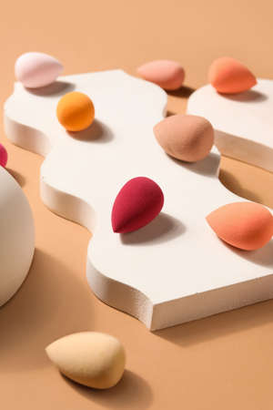 Stand with makeup sponges on beige background