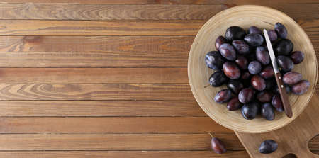 Plate of tasty plums on wooden background with space for text, top viewの写真素材