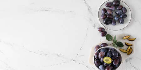 Plates with tasty plums on light background with space for textの写真素材
