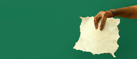Hand of zombie with blank paper sheet on green background. halloween concept