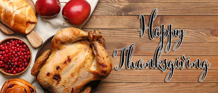 Tasty baked turkey and different food for Thanksgiving day on wooden table