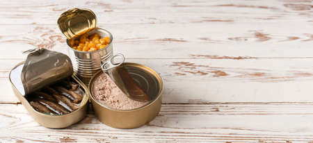 Tin cans with different food on white wooden background with space for textの写真素材
