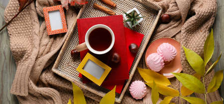 Autumn composition with cup of tea, books, wicker tray and knitted clothes, top view