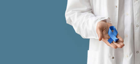 Doctor holding blue ribbon on color background with space for text, closeup. Prostate cancer awareness conceptの写真素材