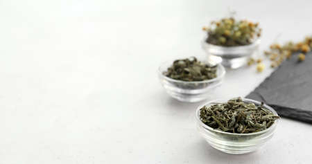 Bowls with dry tea leaves on white table