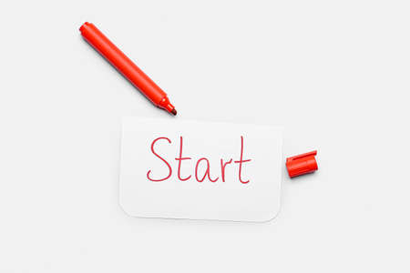 Paper sheet with word START and red marker on white background