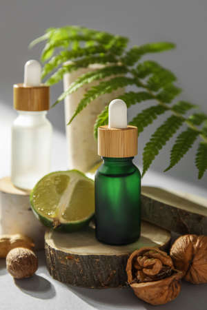 Composition with bottles of essential oil, walnuts and lime on light background, closeup