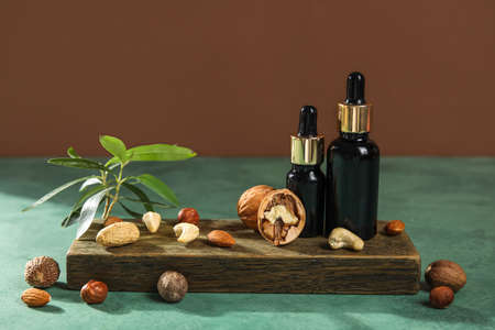 Wooden board with bottles of essential oil and nuts on tableの写真素材