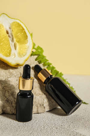 Bottles of essential oil, lemon and stone on table, closeupの写真素材