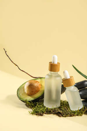 Composition with bottles of essential oil, avocado and moss on color backgroundの写真素材