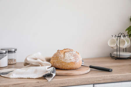 Cutting board with fresh bread and napkin on kitchen counter near light wallの写真素材