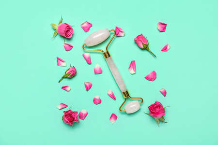 Facial massage tool with roses and petals on green backgroundの写真素材