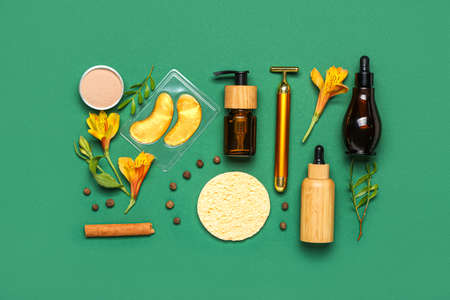 Facial massage tool with cosmetic products and natural components on green background