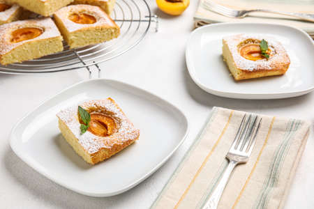 Plates with pieces of tasty apricot pie on light backgroundの写真素材
