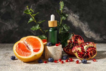 Composition with bottle of essential oil, fruits and berries on tableの写真素材