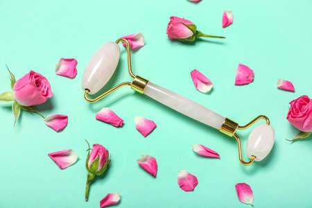Facial massage tool with roses and petals on green backgroundの写真素材