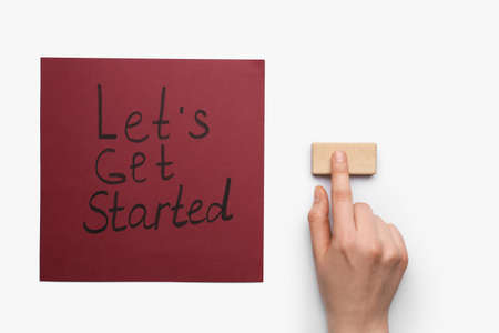 Paper sheet with text LET'S GET STARTED and female hand with wooden block on white background