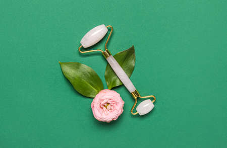 Facial massage tool with flower and leaves on green background