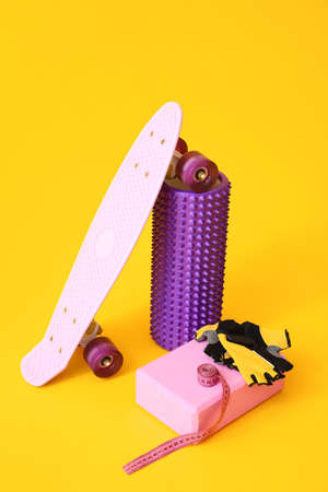 Foam roller with skateboard, block, gloves and measuring tape on yellow backgroundの写真素材