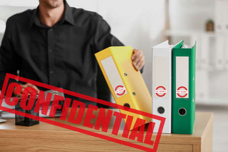 Young man working with top secret documents in officeの写真素材