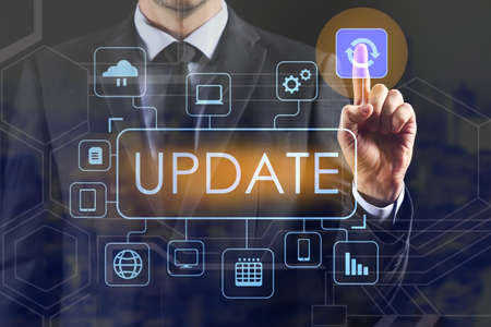 Businessman using virtual screen with word UPDATE on dark background